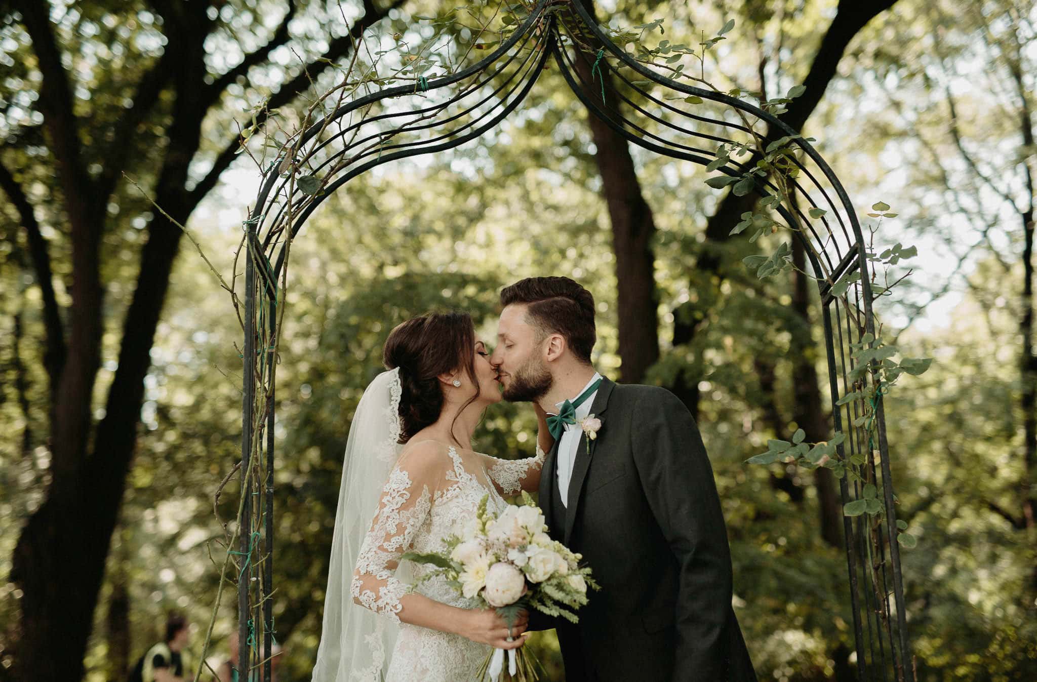 bride kissing her groom under a garden arch