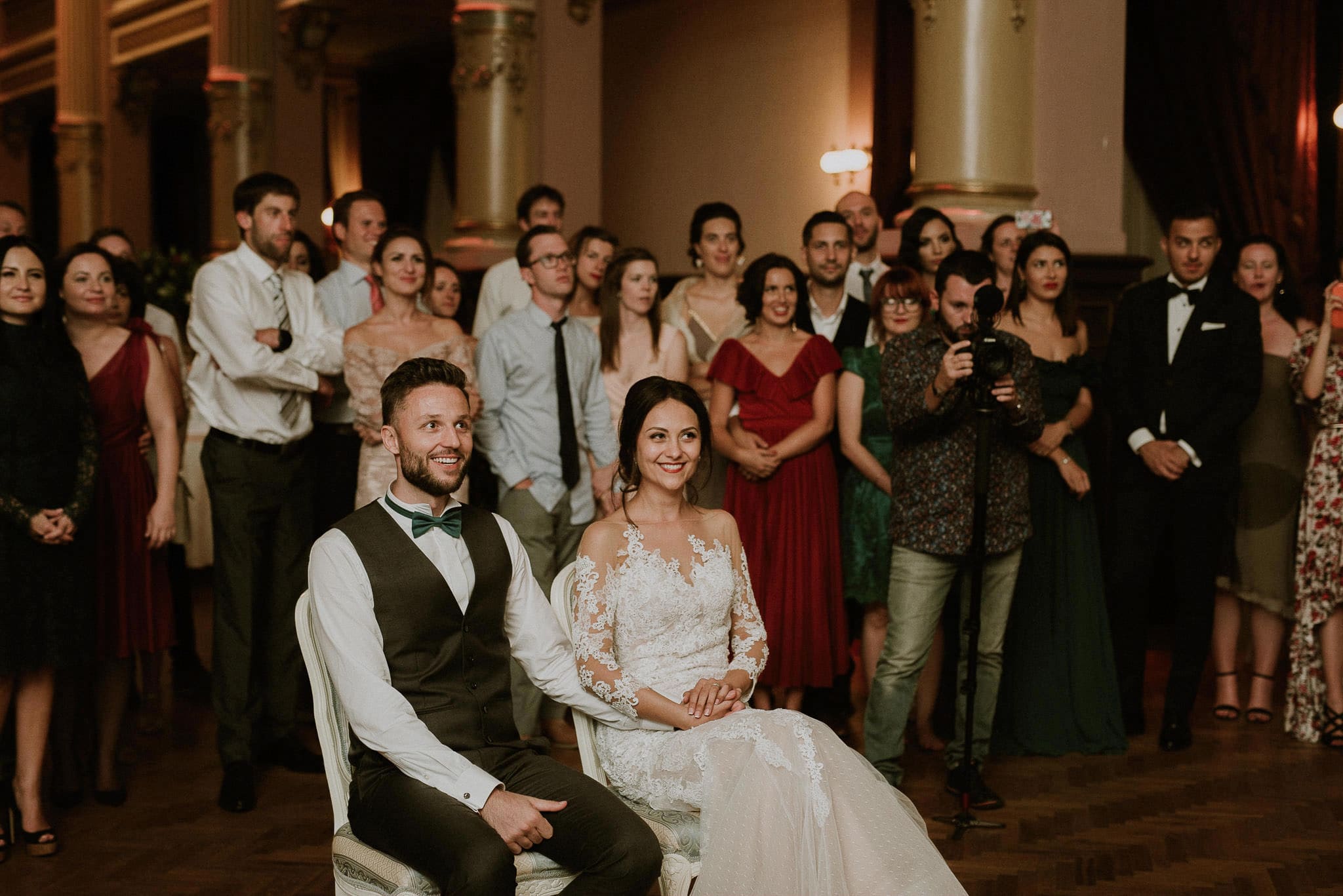 the wedding couple and their guests watch a video during a fun game