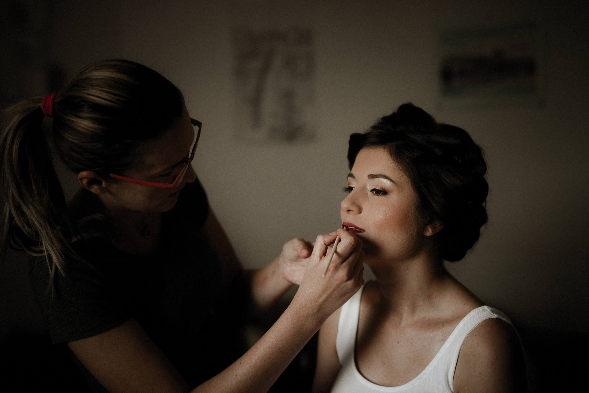 makeup artist applying lipstick to the bride