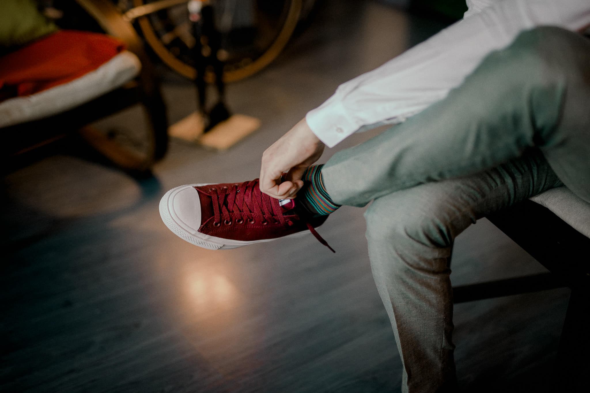 groom putting on converse shoes before his autumn wedding
