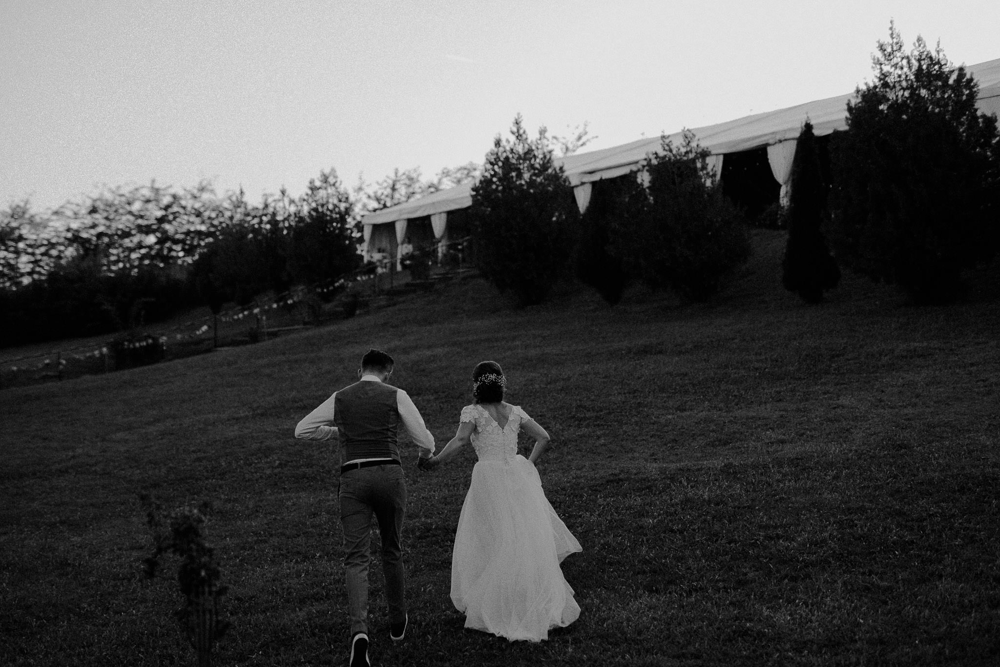 newlyweds run on the lawn outside their autumn wedding venue