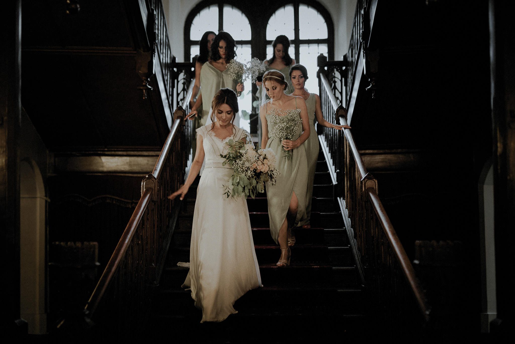 bride and her bridesmaids walking down the stairs towards the ceremony