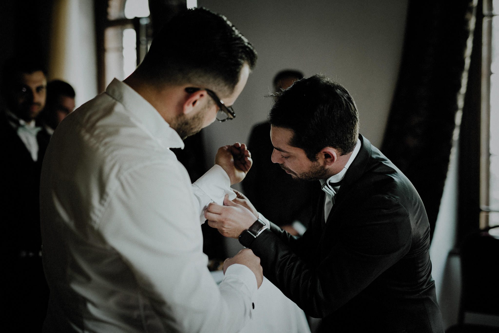 groomsman helping the groom getting dressed on his wedding day