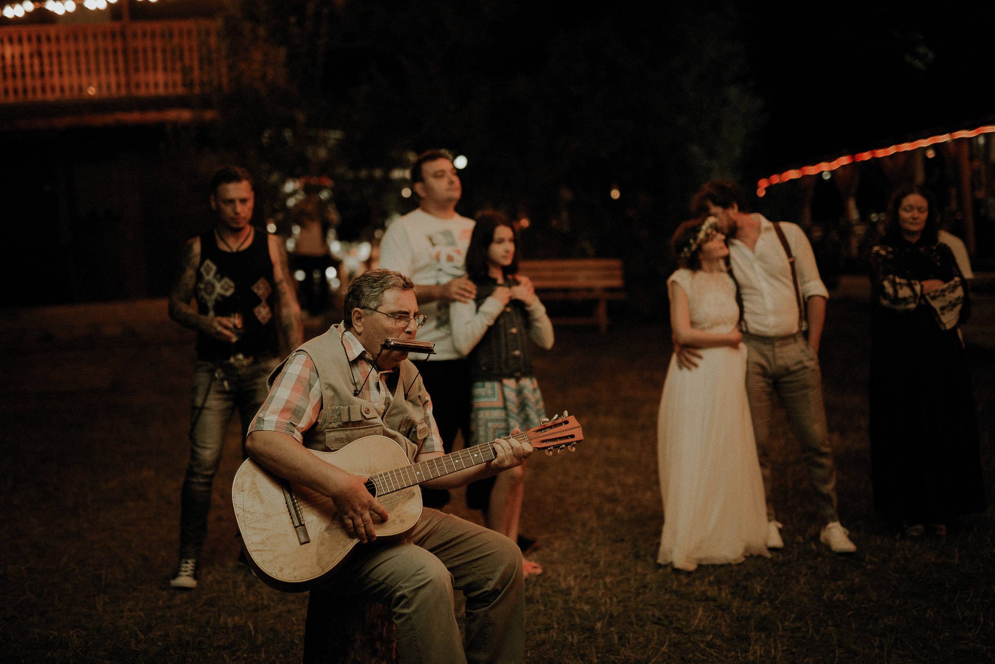 bride's father playing the guitar during wedding party at night in the forest