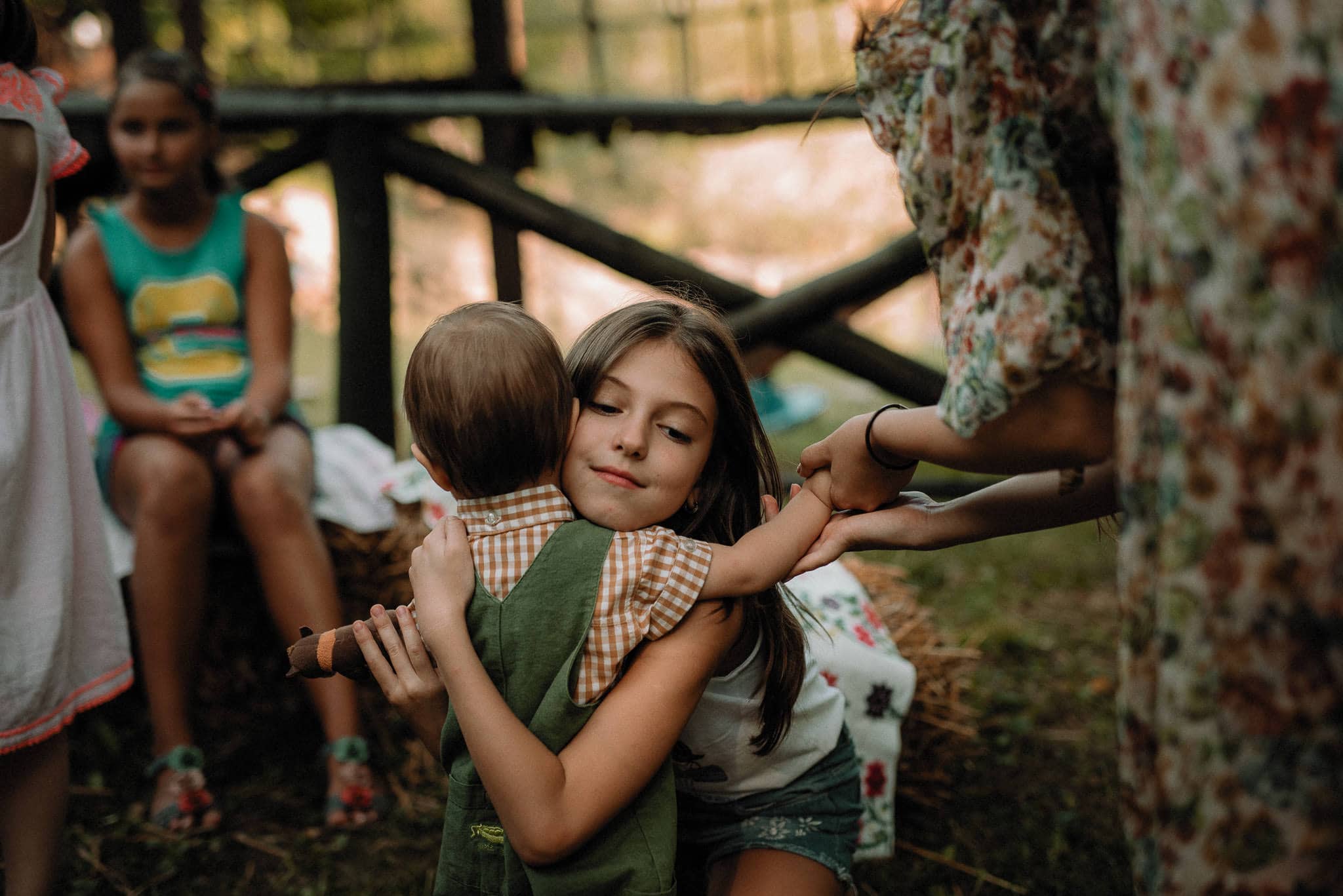 flower girl hugs a little boy during a forest wedding