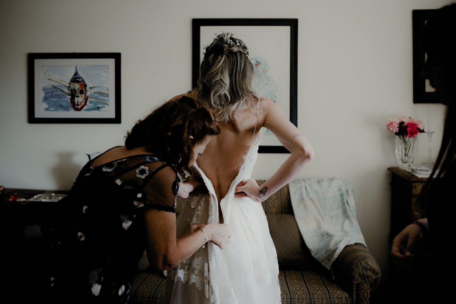 bride helped by her mother to put on her boho wedding dress