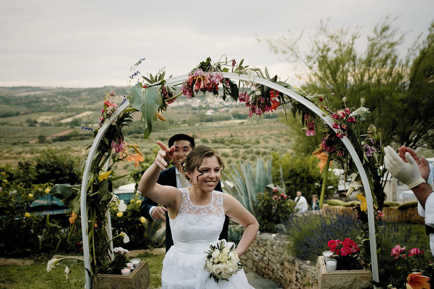 Charming Destination Wedding in the Portuguese Countryside - bride and groom arriving at the party walking underneath the handmade flower arch