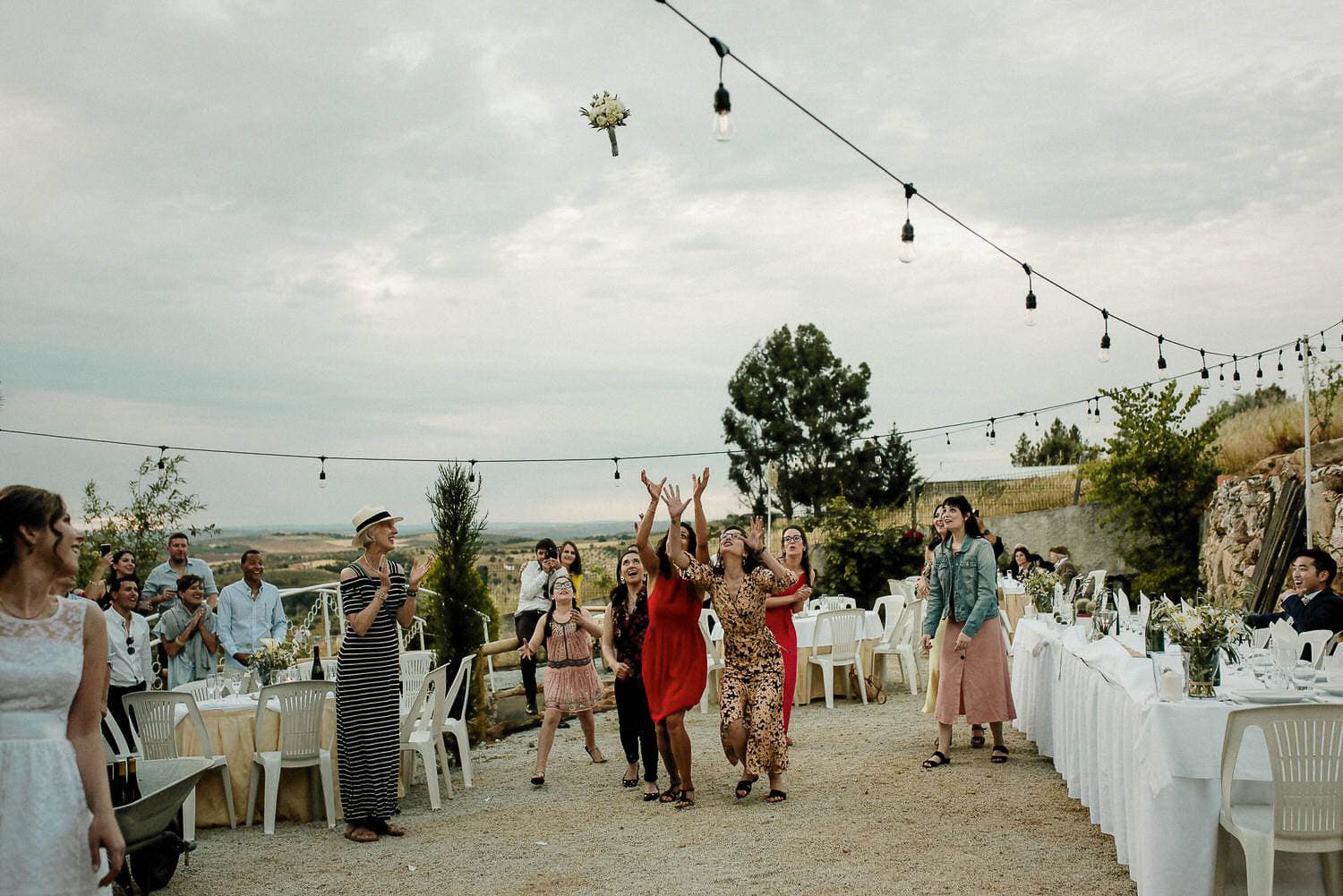 portuguese Wedding in the Portuguese Countryside - bouquet toss with the bridal bouquet flying through the air while the girl try to catch it