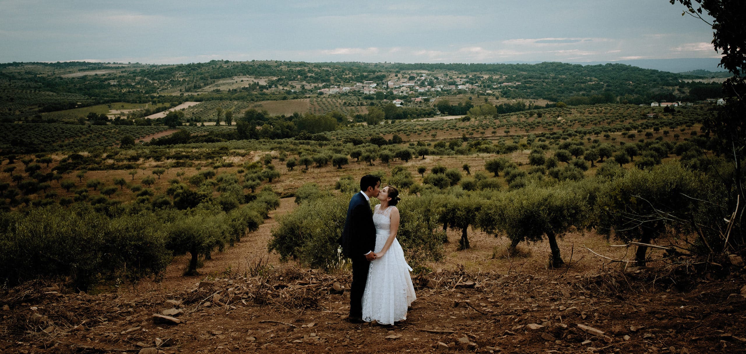 Charming Destination Wedding in the Portuguese Countryside - bride and groom with the hilly landscape and olive trees behind them